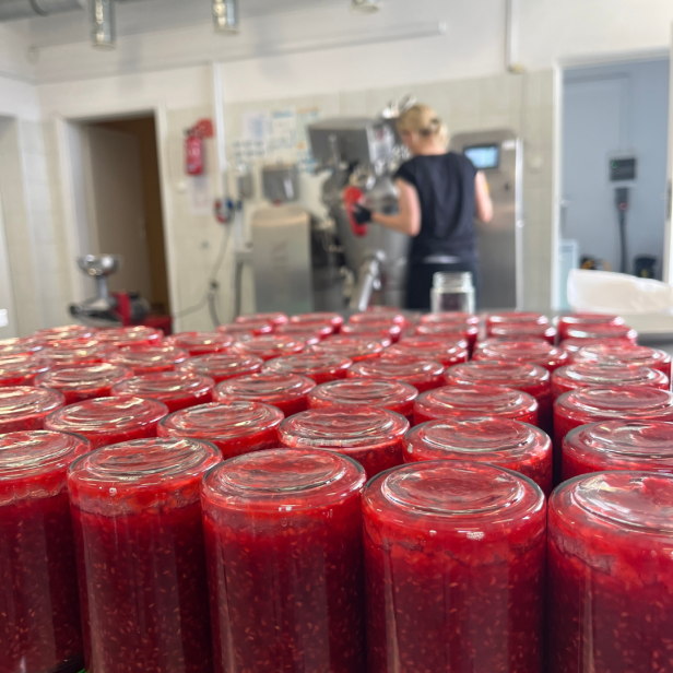 linia produkcyjna konfitury malinowe w oddali maszyna i kobieta pracuje